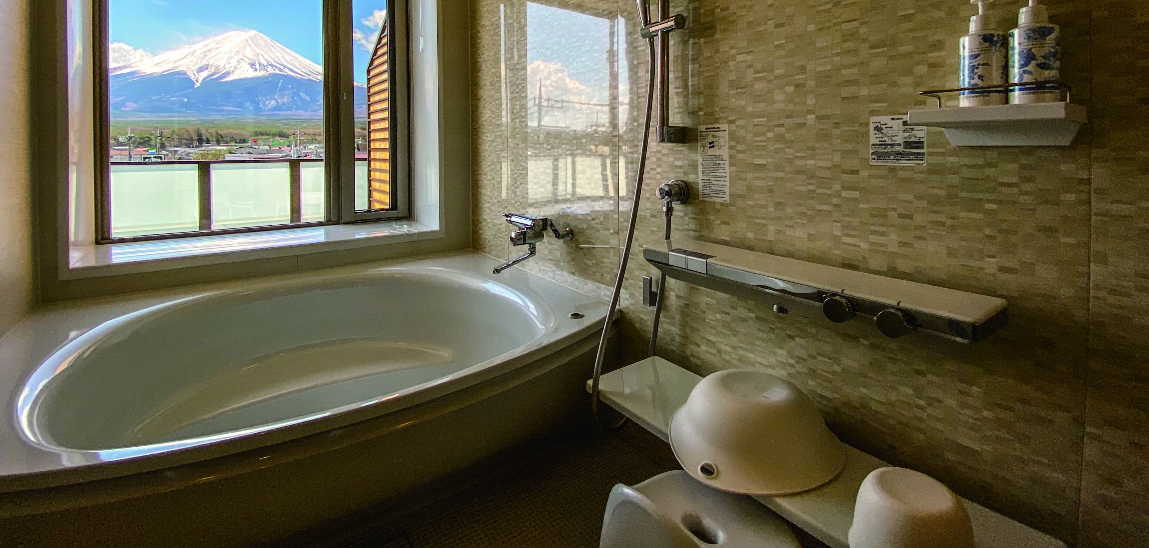 A bathroom with a large bathtub, a shower, and a toilet. There is a window with a view of mountains.