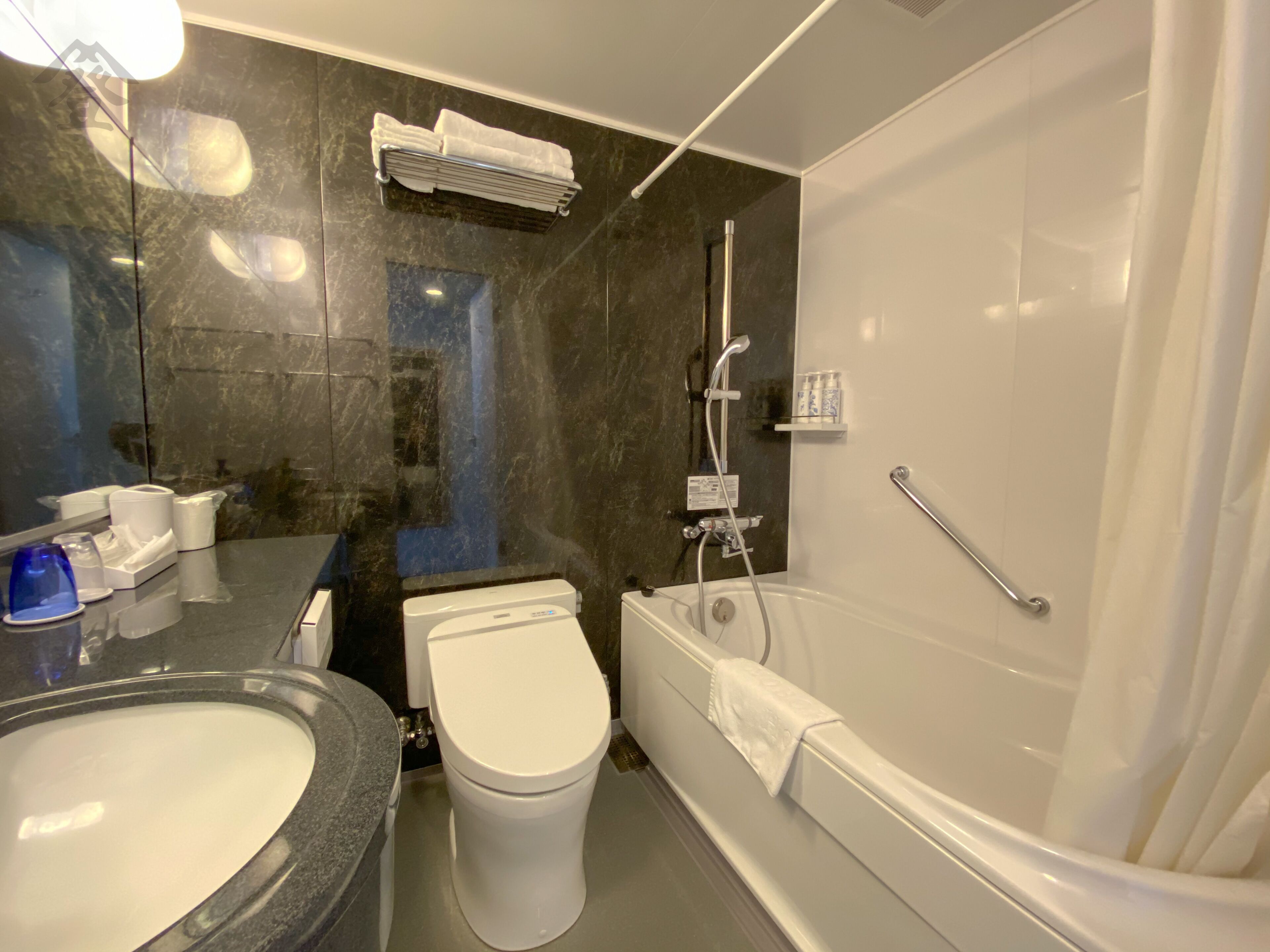 A modern bathroom with a marble vanity, a toilet, a bathtub, and a shower.