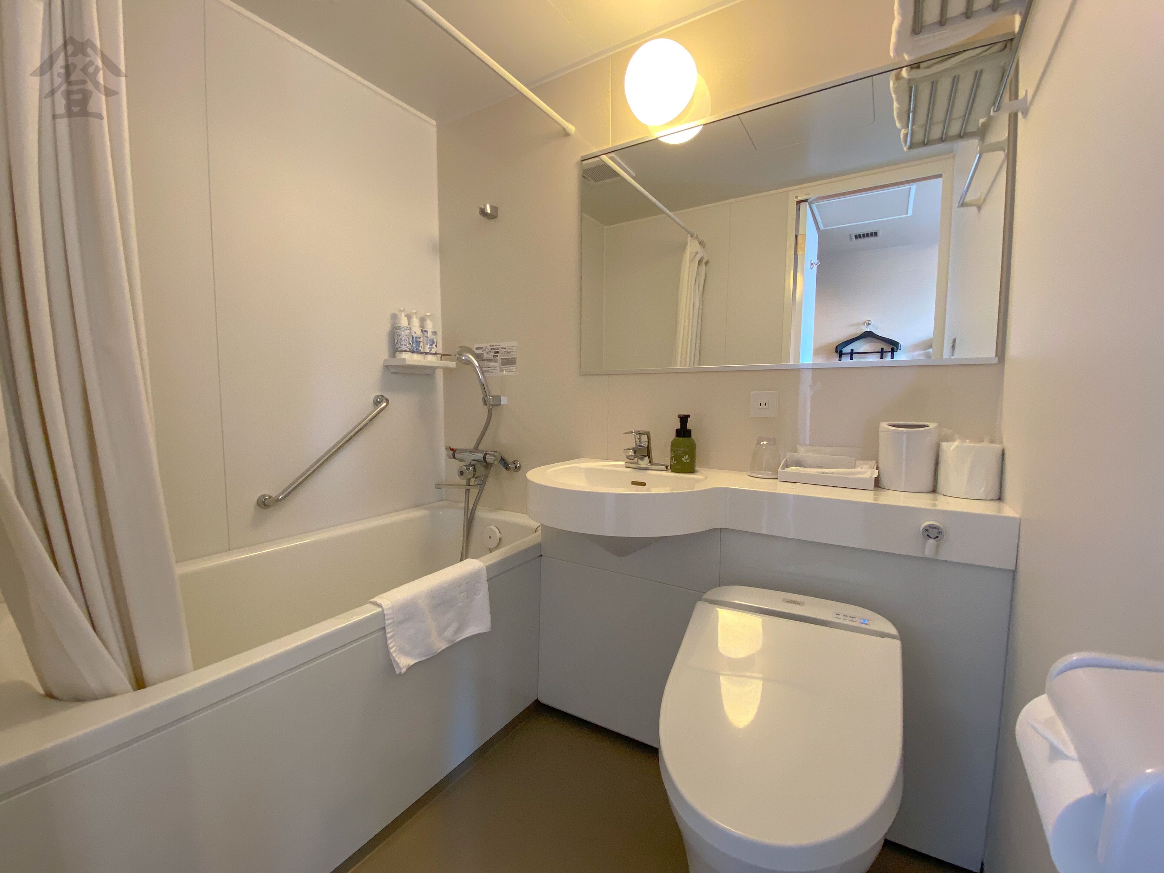 A bathroom with a bathtub, a sink, a toilet, and a mirror.