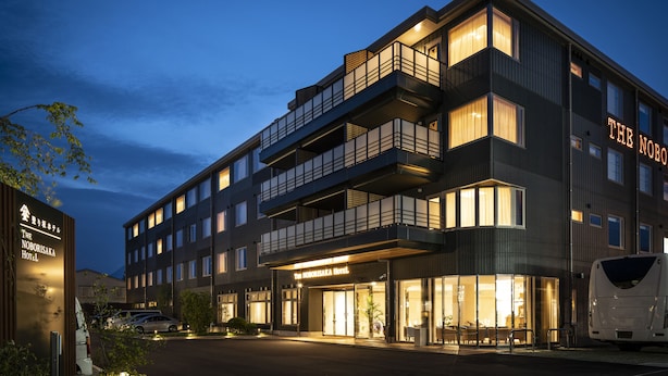 A modern hotel with multiple floors, balconies, and a well-lit entrance. - The Noborisaka Hotel (Fujikawaguchiko)