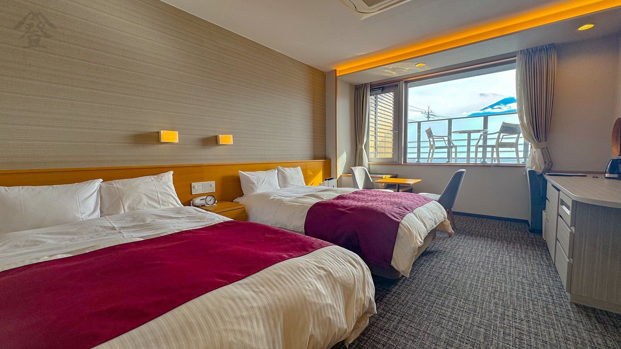 Une chambre d’hôtel avec deux lits, un bureau, une chaise et une vue sur la mer.