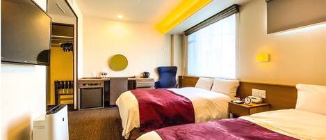 A hotel room with two beds, a desk, a chair, a minibar, and a TV.