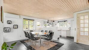 A modern kitchen with white cabinets, a dining area with a round table and black chairs, and a wooden ceiling. - Amazing home in Ulfborg with kitchen (Ulfborg)