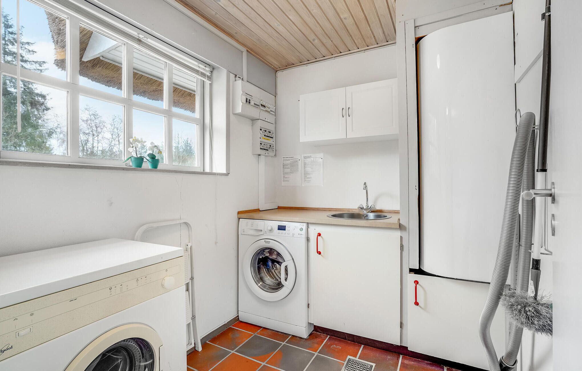 A compact kitchen with a washing machine, a sink, and a refrigerator.