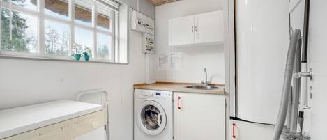 A compact kitchen with a washing machine, a sink, and a refrigerator.