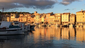 Un port de plaisance avec des bateaux amarrés, une ville riveraine avec des bâtiments et un ciel dégagé.