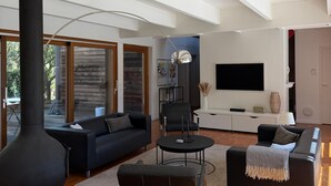 Un salon moderne avec une cheminée, des canapés, une table basse et un téléviseur.