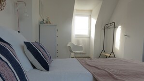 Un dormitorio con una cama, una silla, un radiador y una ventana.