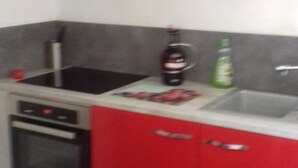 A kitchen with red cabinets, a stainless steel range hood, a stove, and a sink. - Penty for rent in a small village typical of the peninsula (crozon)