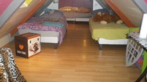 A small attic bedroom with two beds, a wooden floor, and a sloped ceiling. - Penty for rent in a small village typical of the peninsula (crozon)
