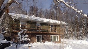 Un bâtiment à deux étages, doté d’une façade en pierre et d’un toit plat, entouré d’arbres couverts de neige.