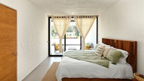 Une chambre à coucher avec une tête de lit en bois, un grand lit avec une literie blanche, un plancher en bois et une vue à travers une porte vitrée.