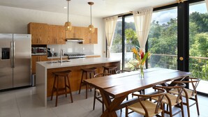 Une cuisine moderne avec des meubles en bois, des appareils en acier inoxydable et un grand îlot central doté de tabourets de bar.