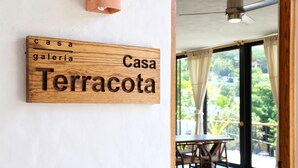 Une enseigne en bois portant l’inscription « Casa Galeria Casa Terracota », fixée à un mur blanc.