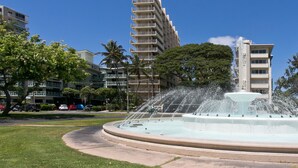 Una fuente con chorros de agua en un parque, con edificios al fondo.
