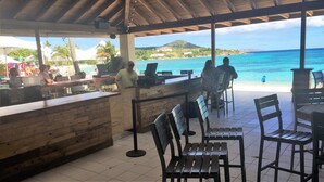A beachside restaurant with a wooden counter and chairs facing the ocean. - Your Perfect Beachfront Condo in Paradise - Sapphire Beach - Corner Unit (St Thomas)