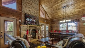 Ein gemütliches Blockhaus-Interieur mit Kamin, Ledersofas und Essbereich.