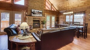 Un interior cálido de cabaña con chimenea, asientos de cuero y amplios ventanales.