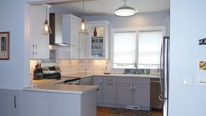 A modern kitchen with white cabinetry, a built-in oven, and pendant lighting. -  Beautiful Victorian Home Close to beaches-Close To Downtown/Shops/Restaurants (Traverse City)