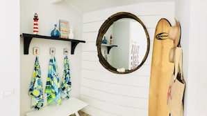 Een badkamer met een wit wastafelmeubel, een ronde spiegel en een plank met decoratieve objecten.