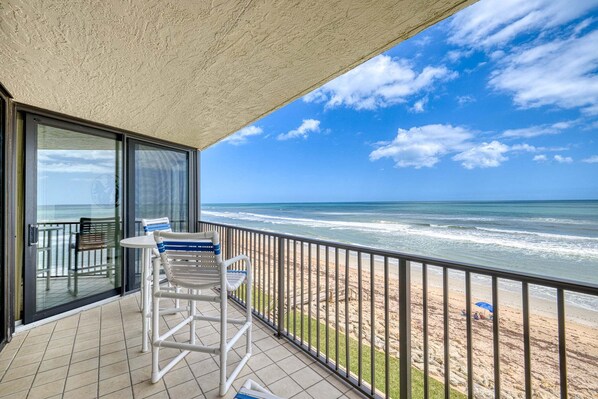 A balcony with a view of the beach and ocean.