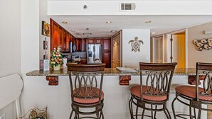 Una cocina con armarios de madera, un refrigerador y una encimera con taburetes de bar.