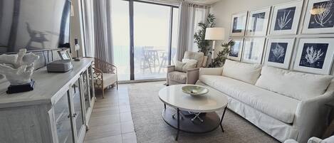 Una sala de estar moderna con un sofá, sillones, una mesa de centro y un ventilador de techo.