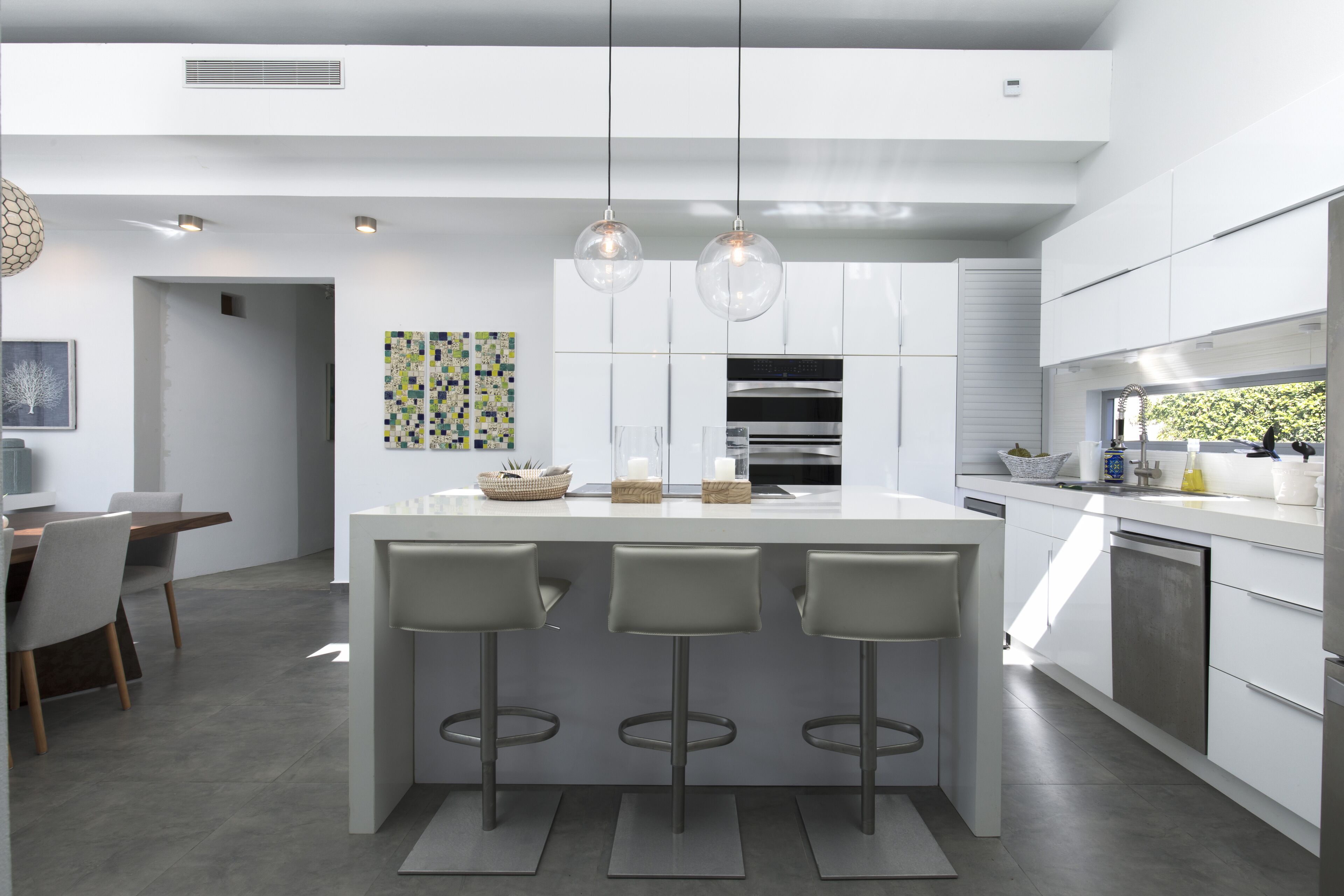 A modern kitchen with a central island, bar stools, pendant lighting, and stainless steel appliances.