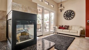 Un salon avec une cheminée, un canapé, un tapis et une horloge murale.