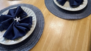 Une table à manger dressée avec des assiettes, des serviettes et des sets de table.