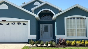 Une maison à deux étages avec un garage, une porte d’entrée et une grande fenêtre.