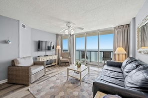 Relax in this stylish living room with a large flat-screen TV, comfortable sofa, and wicker armchair.