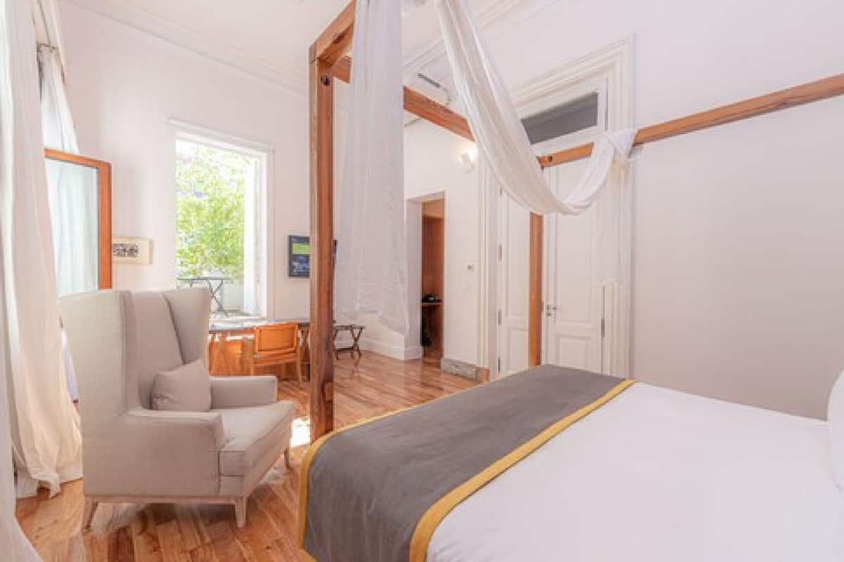 Un dormitorio con cama, una silla, un escritorio y una ventana.