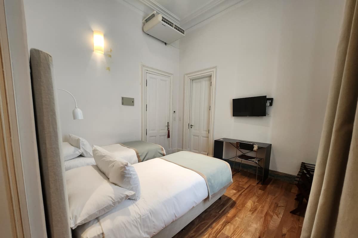 Un dormitorio con cama, escritorio, silla, televisor y armario.