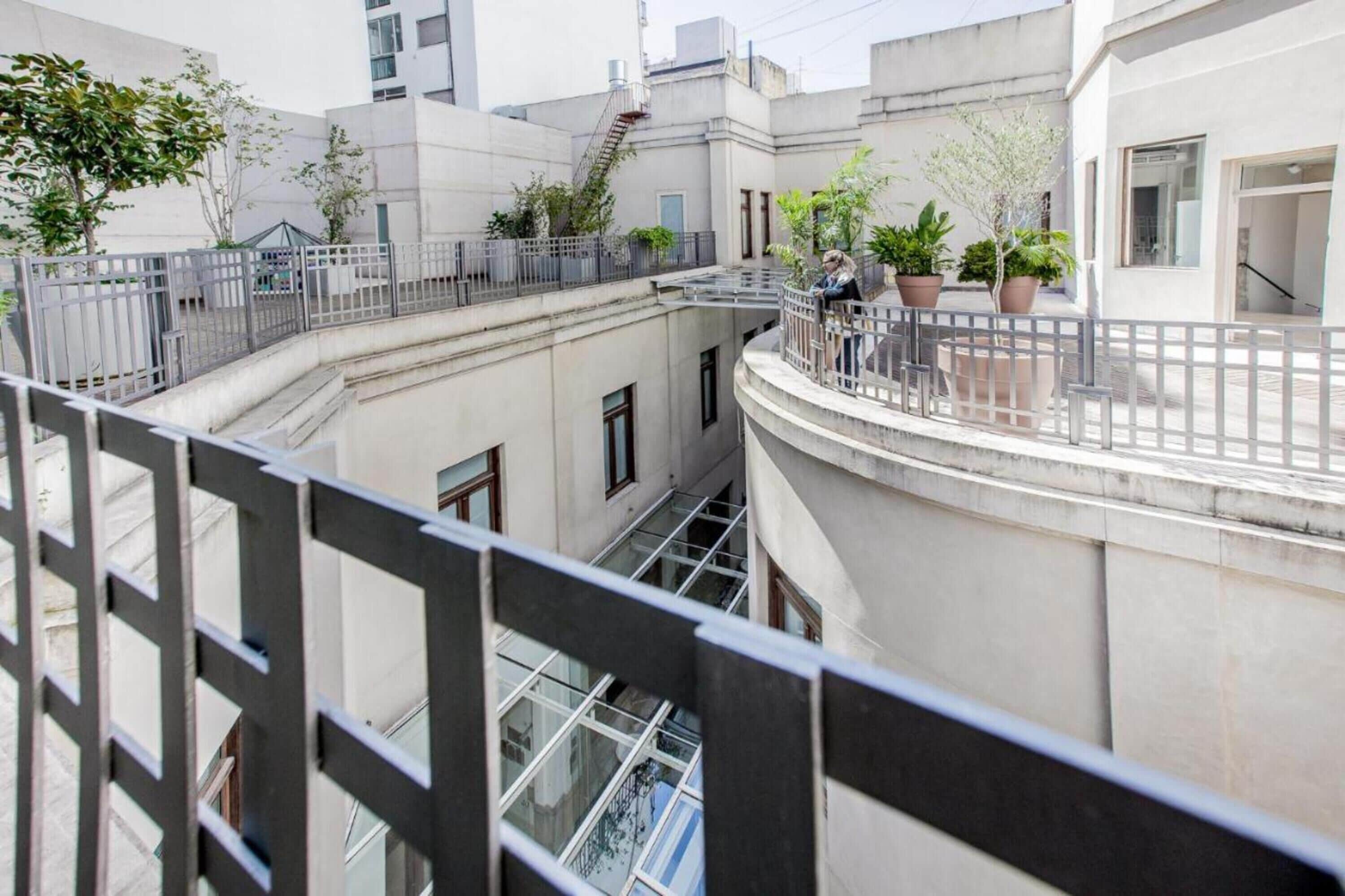 A multi-level residential building with balconies, potted plants, and a staircase.