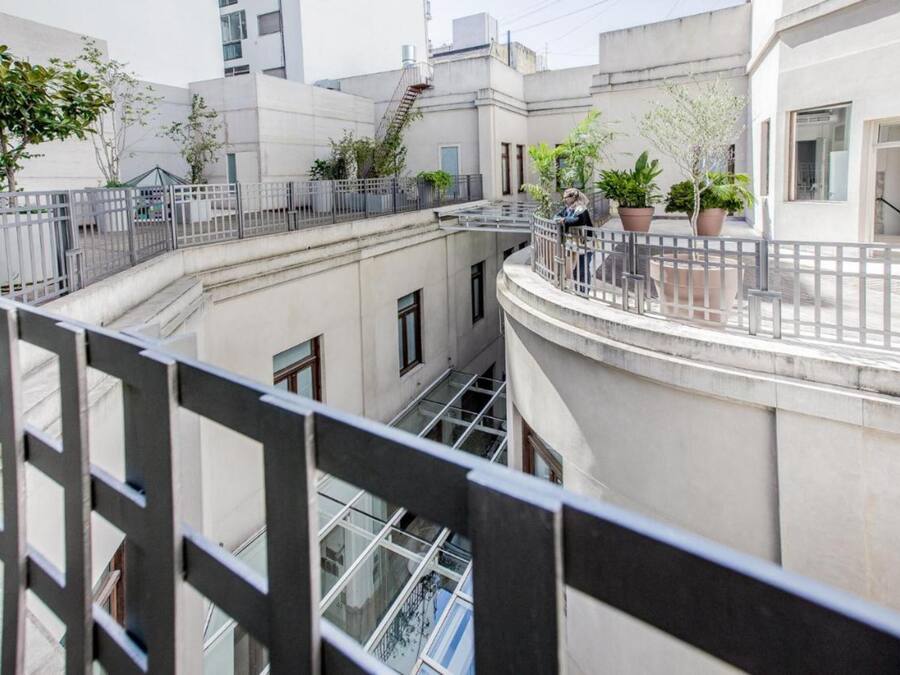 A multi-level residential building with balconies, potted plants, and a staircase.