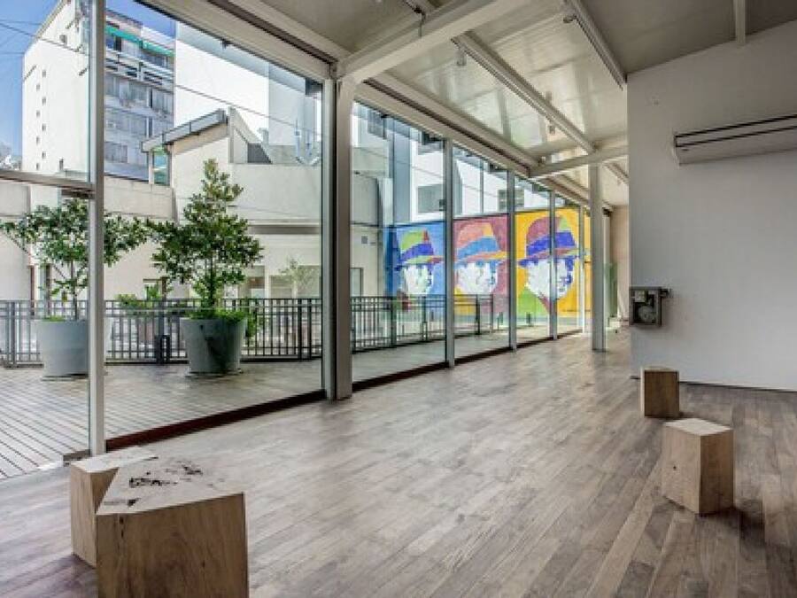 Un interior moderno con ventanas amplias, suelo de madera y vistas a los edificios exteriores.