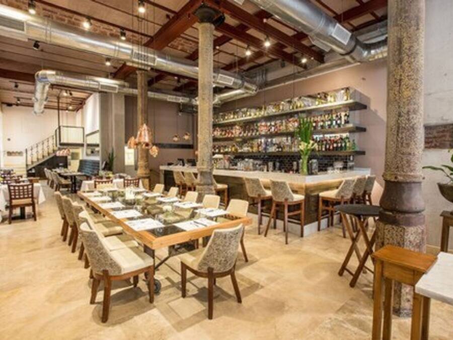 Un restaurant avec de grandes tables où les clients peuvent s’asseoir ensemble et un espace bar.