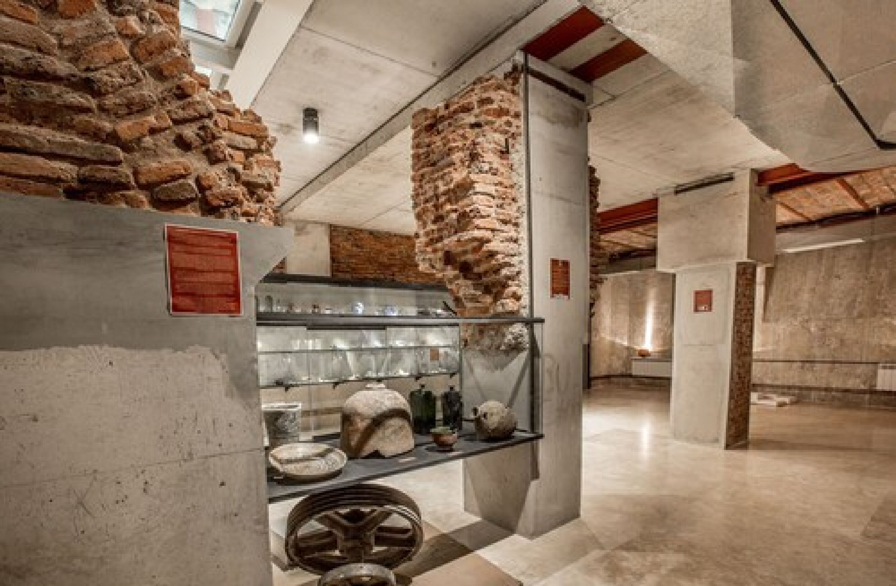 A museum interior with stone walls, a glass display case, and a tiled floor.