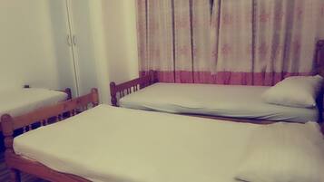 Une chambre avec deux lits simples, chacun doté d’une tête de lit en bois et de draps blancs.