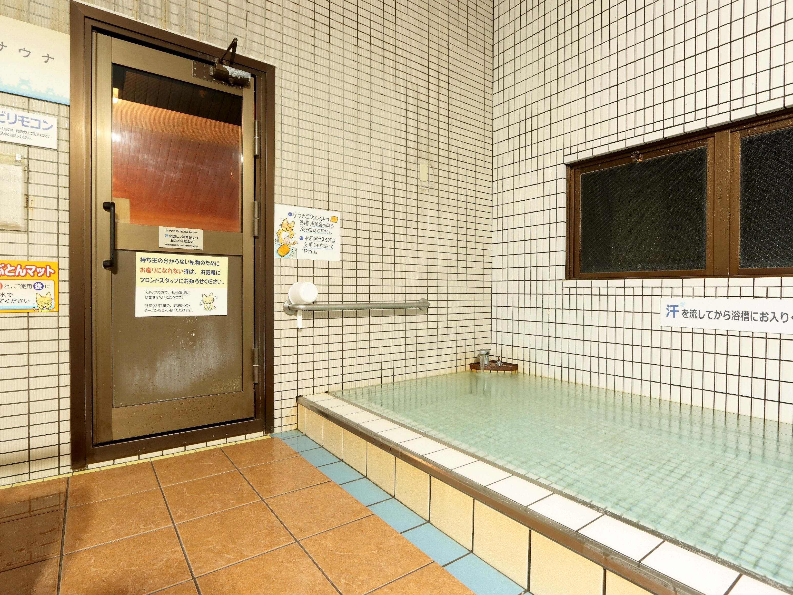 Un bain public avec un mur carrelé, une porte et une fenêtre.