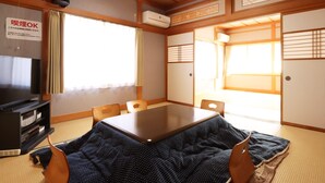 A traditional Japanese room with tatami flooring, a tatami mat table, a television, and an air conditioning unit. - Tuji Wakuwaku Land Minshuku Chaya (Uozu)