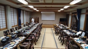 A traditional Japanese-style conference room with tatami flooring, wooden tables, and chairs.