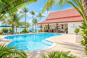Zona junto a la piscina con sillones, un bar y un edificio que indica 'Chaweng Bliss Bungalow'.