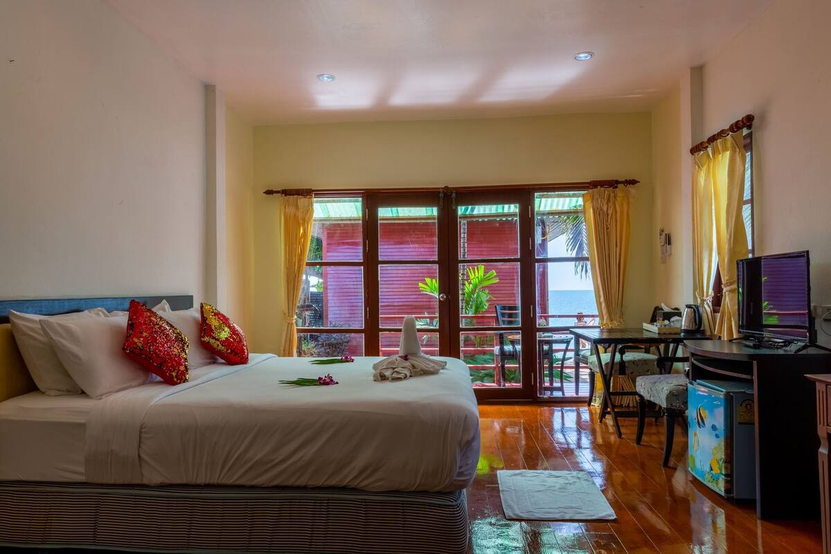 A hotel room with a bed, a desk with a computer, and a view of the outside.