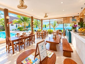 A beachfront restaurant with wooden tables and chairs, a pool, and a view of the ocean. - Chaweng Bliss Bungalow (Koh Samui)