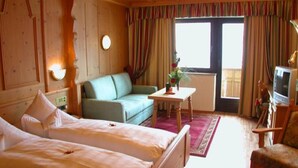 Une chambre d’hôtel avec deux lits, un canapé, une télévision et une fenêtre avec des rideaux.
