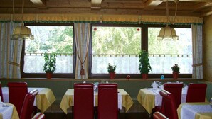 Un restaurant avec des poutres en bois au plafond, des chaises rouges et des tables recouvertes de nappes jaunes.