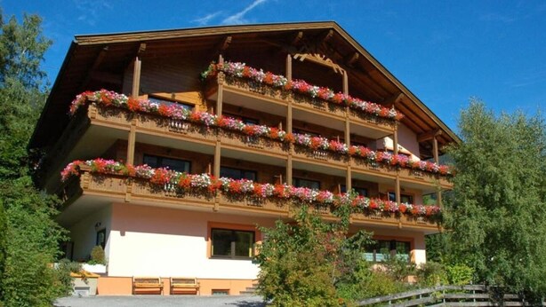 Un immeuble à plusieurs étages dont les balcons sont ornés de fleurs.