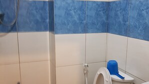 A bathroom with a toilet, a bidet, a blue bucket, and a green trash bin. - Hidden Garden Pension (El Nido)